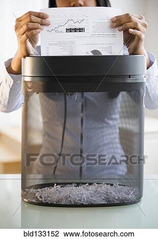 Stock Image - Mixed race businesswoman shredding documents. Fotosearch