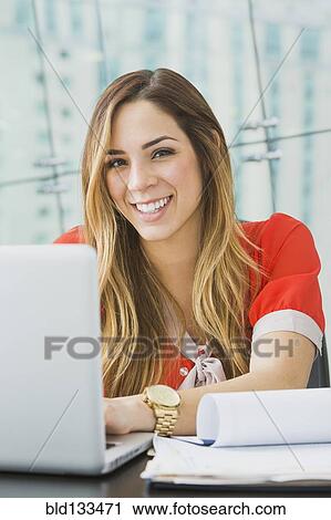 Mixed race businesswoman smiling at desk View Large Photo Image Stock Image - Mixed race businesswoman smiling at desk. Fotosearch