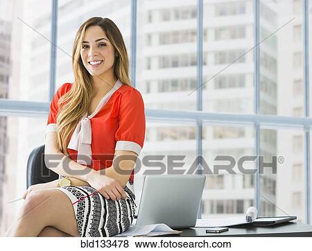 Stock Photo - Mixed race businesswoman smiling at desk. Fotosearch
