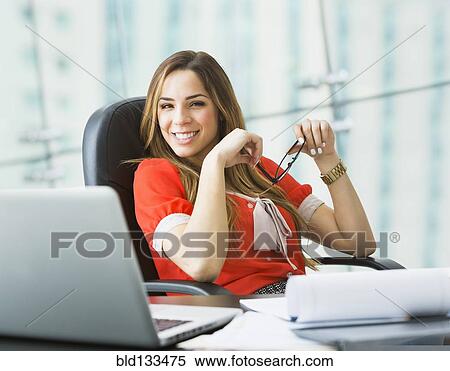 Stock Photography - Mixed race businesswoman smiling at desk. Fotosearch