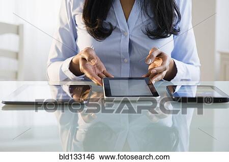 Stock Photograph - Mixed race businesswoman using digital tablets. Fotosearch