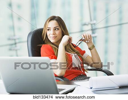 Picture - Mixed race businesswoman working at desk. Fotosearch
