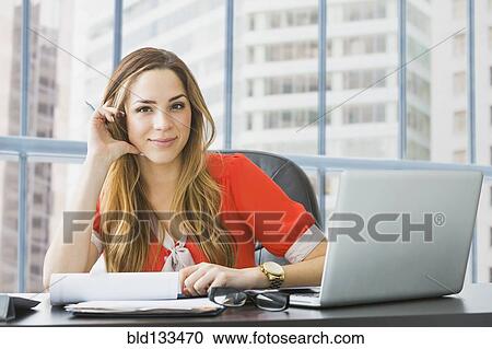 Mixed race businesswoman working at desk View Large Photo Image Stock Image - Mixed race businesswoman working at desk. Fotosearch