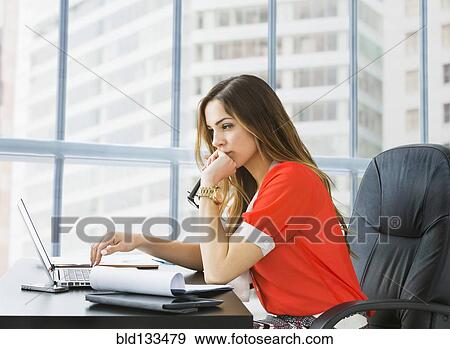 Stock Photo - Mixed race businesswoman working at desk. Fotosearch