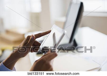 Stock Image - Mixed race businesswoman working on digital tablet. Fotosearch