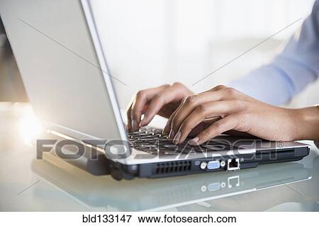 Stock Photo - Mixed race businesswoman working on laptop. Fotosearch