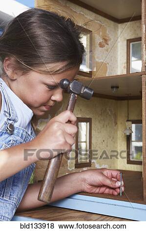 Stock Photo - Mixed race girl fixing doll house. Fotosearch