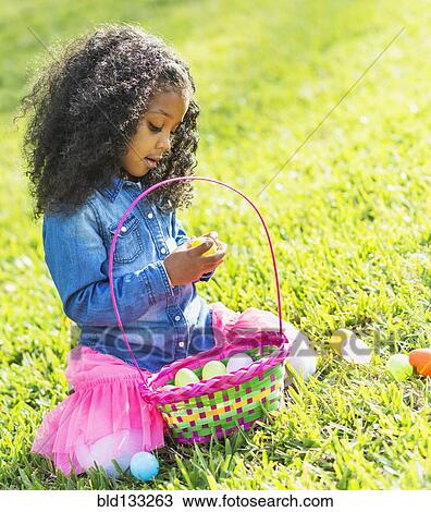 Stock Image - Mixed race girl hunting for Easter eggs. Fotosearch