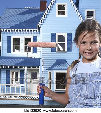 Stock Image - Mixed race girl painting doll house. Fotosearch