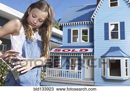 Stock Image - Mixed race girl playing with doll house. Fotosearch