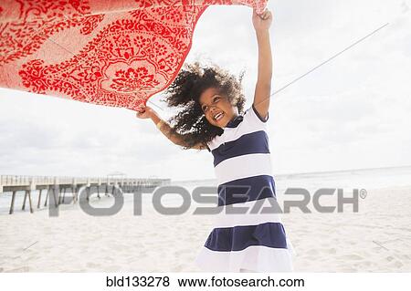 Mixed race girl playing with towel on beach View Large Photo Image Stock Photo - Mixed race girl playing with towel on beach. Fotosearch