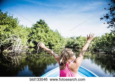 Stock Photograph - Mixed race girl sitting in canoe in still lake. Fotosearch