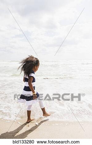 Mixed race girl walking in waves on beach View Large Photo Image Stock Image - Mixed race girl walking in waves on beach. Fotosearch