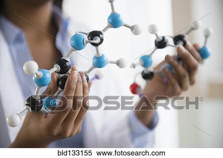 Stock Photography - Mixed race scientist examining molecular model. Fotosearch
