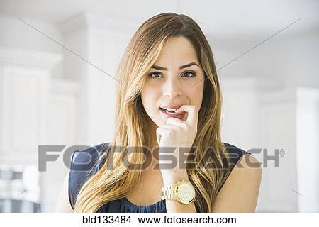 Picture - Mixed race woman biting her nail. Fotosearch