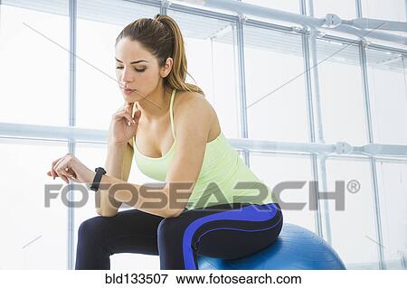 Mixed race woman checking her pulse in gym View Large Photo Image Stock Photo - Mixed race woman checking her pulse in gym. Fotosearch