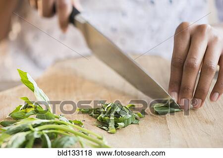 Stock Photo - Mixed race woman chopping herbs. Fotosearch
