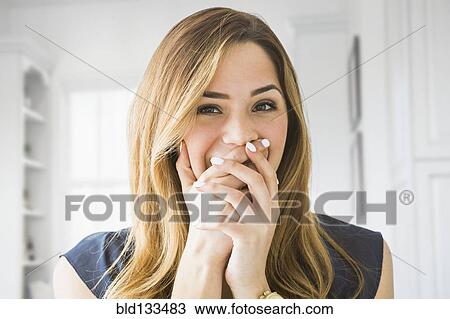 Stock Image - Mixed race woman covering her mouth at home. Fotosearch