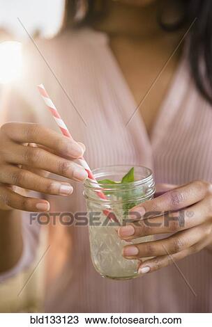 Stock Image - Mixed race woman drinking cocktail. Fotosearch