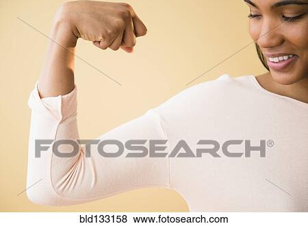 Stock Photo - Mixed race woman flexing her muscles. Fotosearch