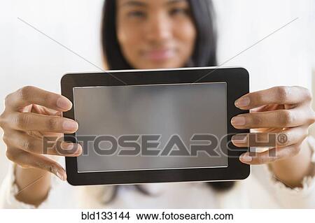 Picture - Mixed race woman holding digital tablet. Fotosearch