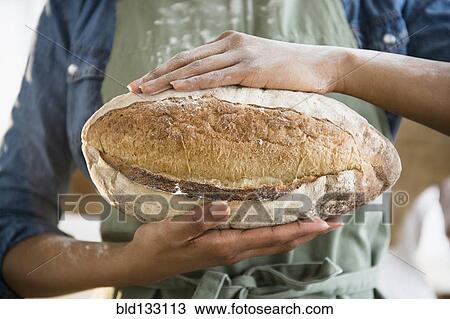 Stock Image - Mixed race woman holding loaf of bread. Fotosearch