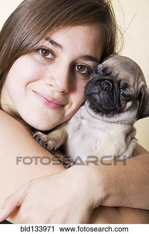 Stock Image - Mixed race woman hugging pug. Fotosearch