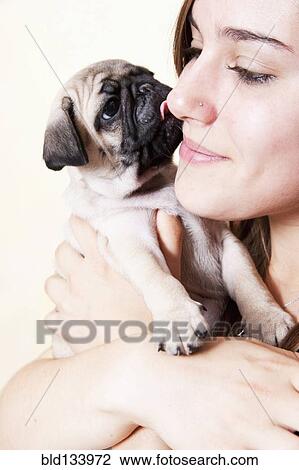Stock Image - Mixed race woman hugging pug. Fotosearch