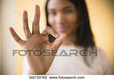 Stock Image - Mixed race woman making OK symbol. Fotosearch