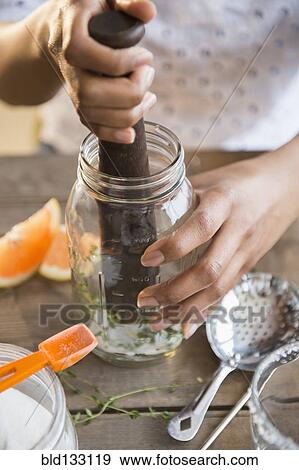 Stock Photo - Mixed race woman muddling cocktail. Fotosearch