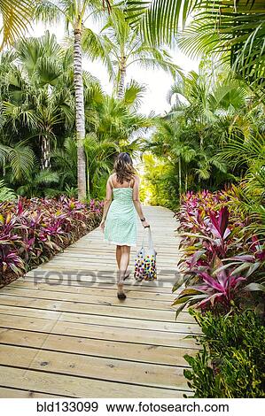 Stock Photo - Mixed race woman on tropical walkway. Fotosearch