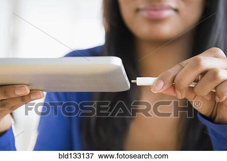Mixed race woman plugging in digital tablet View Large Photo Image Stock Photo - Mixed race woman plugging in digital tablet. Fotosearch