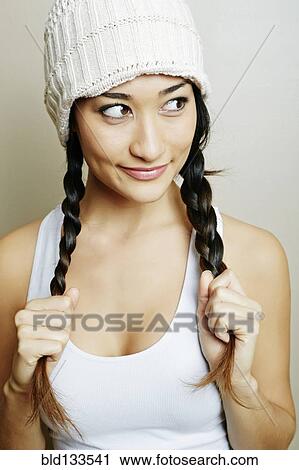 Stock Image - Mixed race woman pulling her pigtails. Fotosearch