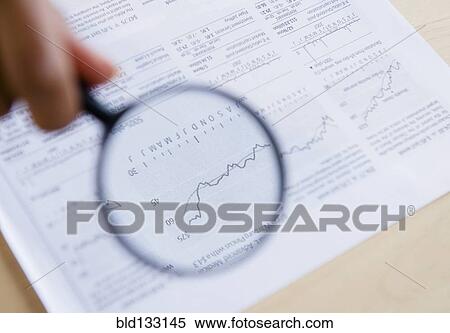 Stock Photography - Mixed race woman reading graph with magnifying glass. Fotosearch