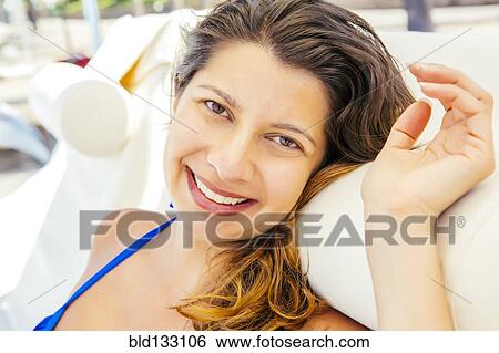 Stock Photograph - Mixed race woman relaxing on beach. Fotosearch