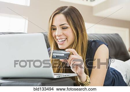 Picture - Mixed race woman shopping online on sofa. Fotosearch