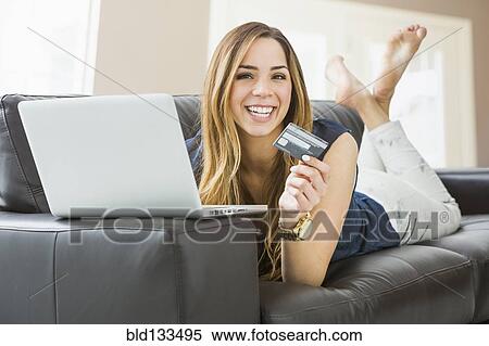 Stock Photography - Mixed race woman shopping online on sofa. Fotosearch