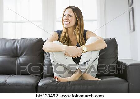 Stock Image - Mixed race woman smiling on sofa. Fotosearch