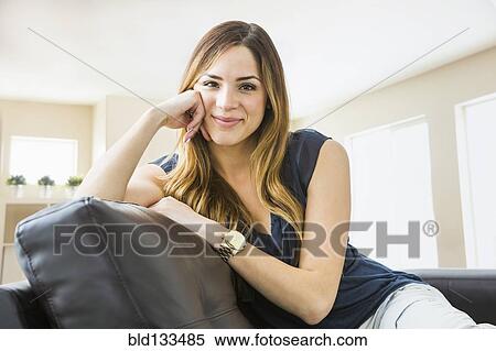 Stock Photography - Mixed race woman smiling on sofa. Fotosearch