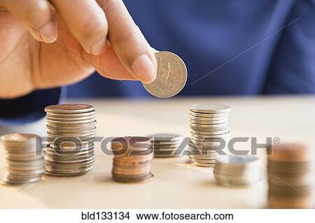 Picture - Mixed race woman stacking coins. Fotosearch
