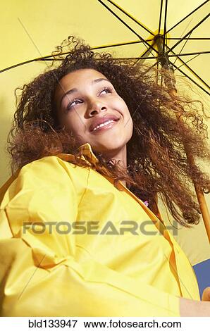 Stock Photo - Mixed race woman standing under umbrella. Fotosearch
