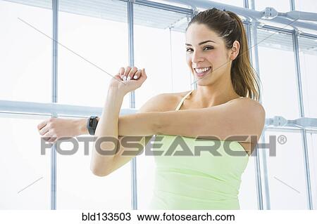 Stock Image - Mixed race woman stretching in gym. Fotosearch