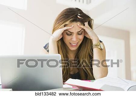 Stock Image - Mixed race woman studying at home. Fotosearch