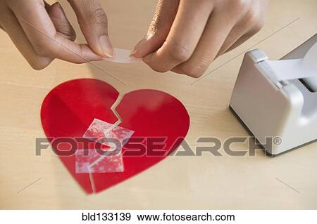 Stock Photo - Mixed race woman taking broken paper heart. Fotosearch