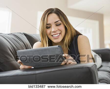 Mixed race woman using digital tablet on sofa View Large Photo Image Stock Photo - Mixed race woman using digital tablet on sofa. Fotosearch