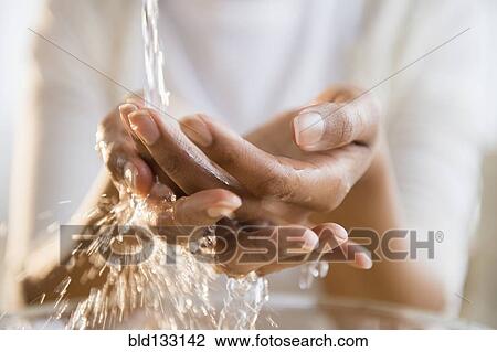 Stock Image - Mixed race woman washing her hands. Fotosearch