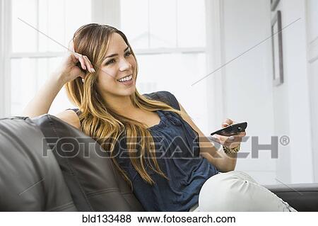 Mixed race woman watching television on sofa View Large Photo Image Stock Photo - Mixed race woman watching television on sofa. Fotosearch