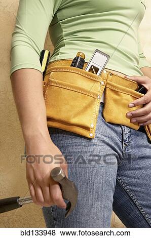 Mixed race woman wearing tool belt View Large Photo Image Stock Photo - Mixed race woman wearing tool belt. Fotosearch