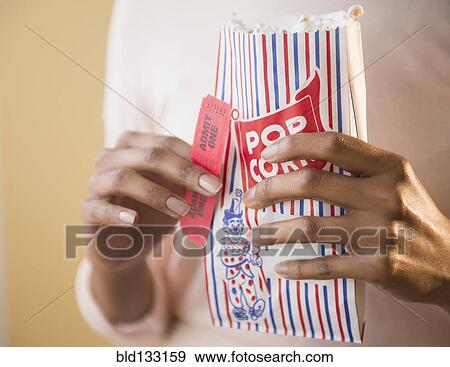 Mixed race woman with bag of popcorn and movie tickets View Large Photo Image Stock Photo - Mixed race woman with bag of popcorn and movie tickets. Fotosearch