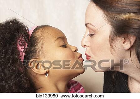 Stock Image - Mother and daughter kissing. Fotosearch